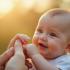 Baby hand omwikkeld rond een volwassen vinger, symbolisch voor liefde en bescherming.