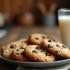 Een bord met warme chocolate chip cookies met een glas melk