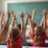 Een klaslokaal met kinderen die hun handen opsteeken om vragen te stellen