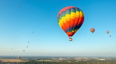 Een kleurrijke luchtballon boven Belgisch landschap