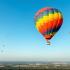 Een kleurrijke luchtballon boven Belgisch landschap