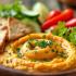 Een kleurrijke schaal met hummus, groenten en pita-brood.
