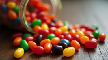 Een kleurrijke verzameling jelly beans verspreid op een houten tafel.