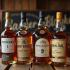Een selectie van whiskyflessen op een houten tafel.