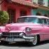 Een vintage roze Cadillac in een levendige stedelijke omgeving