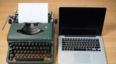 Een vintage typemachine naast een moderne laptop