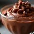 Een weelderige chocolademousse in een elegante glazen kom met chocoladekrullen bovenop.