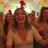 Groep mensen danst de kipdans op een kleurrijk feest.