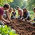 Groep mensen die deelnemen aan een composteerworkshop in een tuin.