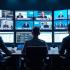 Journalisten aan het werk in een drukke redactiekamer, omringd door monitors met wereldnieuws.