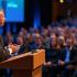 Spreker op het podium voor enthousiast publiek.